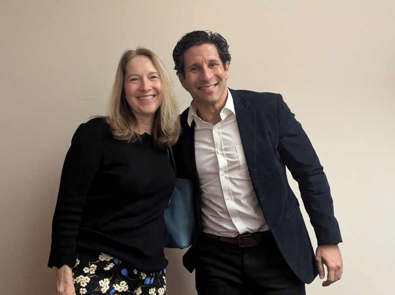 Photo: Babak Ziai and Mary Lynne Boorn stand together and smile for a photo in front of a cream-colored interior wall.