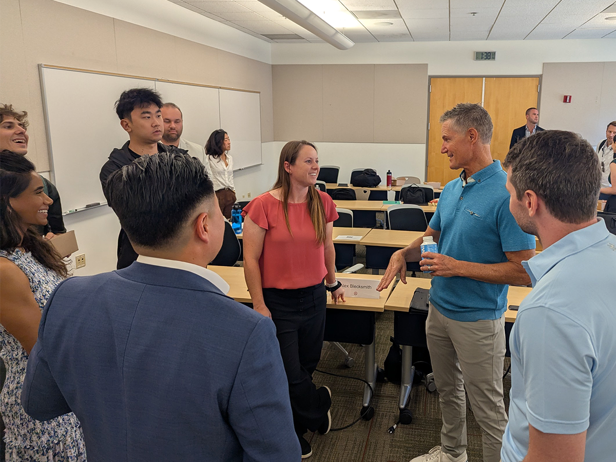 BJ Delzer stands and talks with a small crowd of seven students.