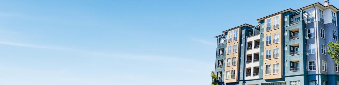 Photo: A multistory apartment building on a sunny day with a blue sky background.